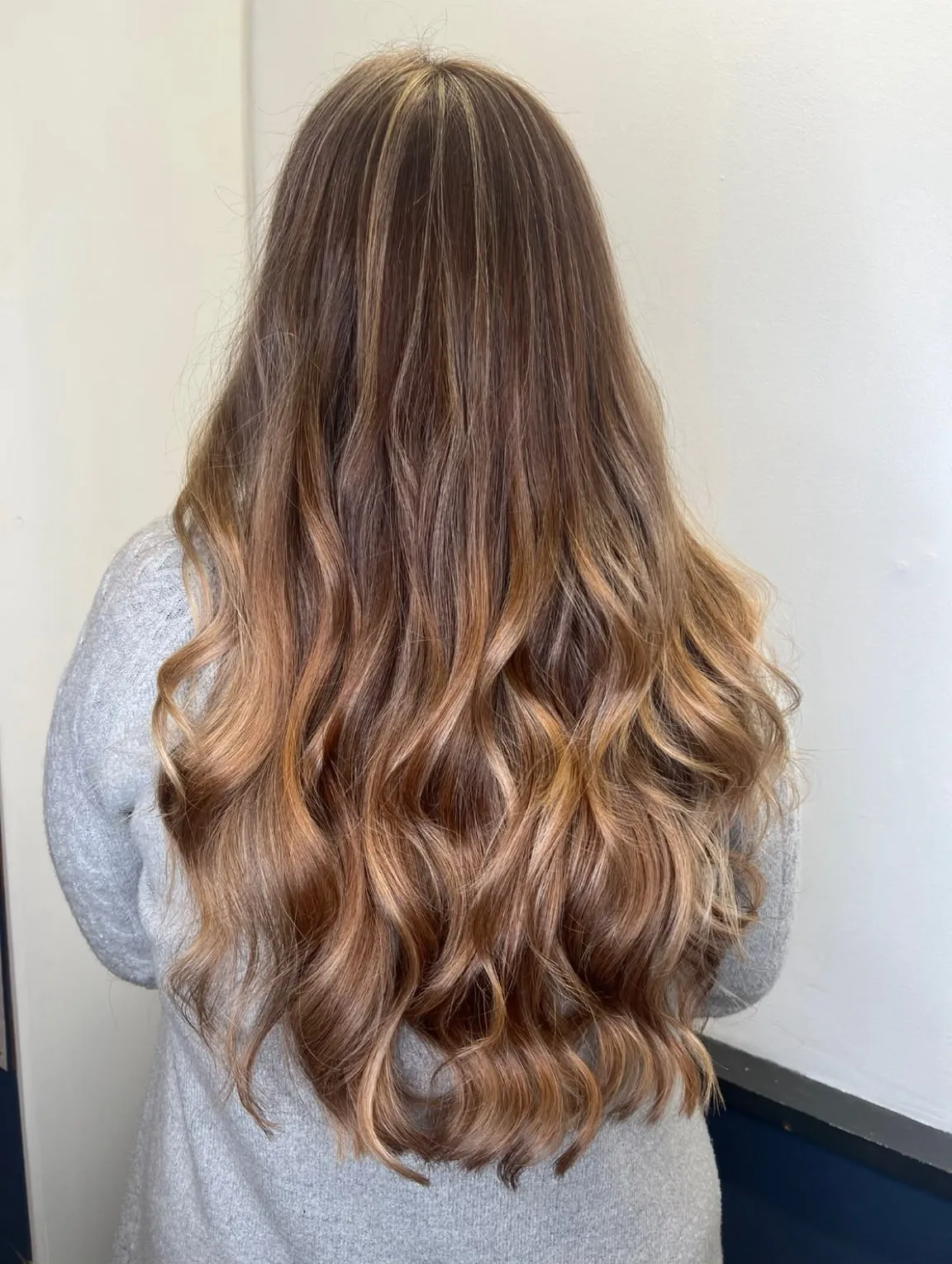 Soft brunette balayage melting into golden caramel lengths, long and loosely curled