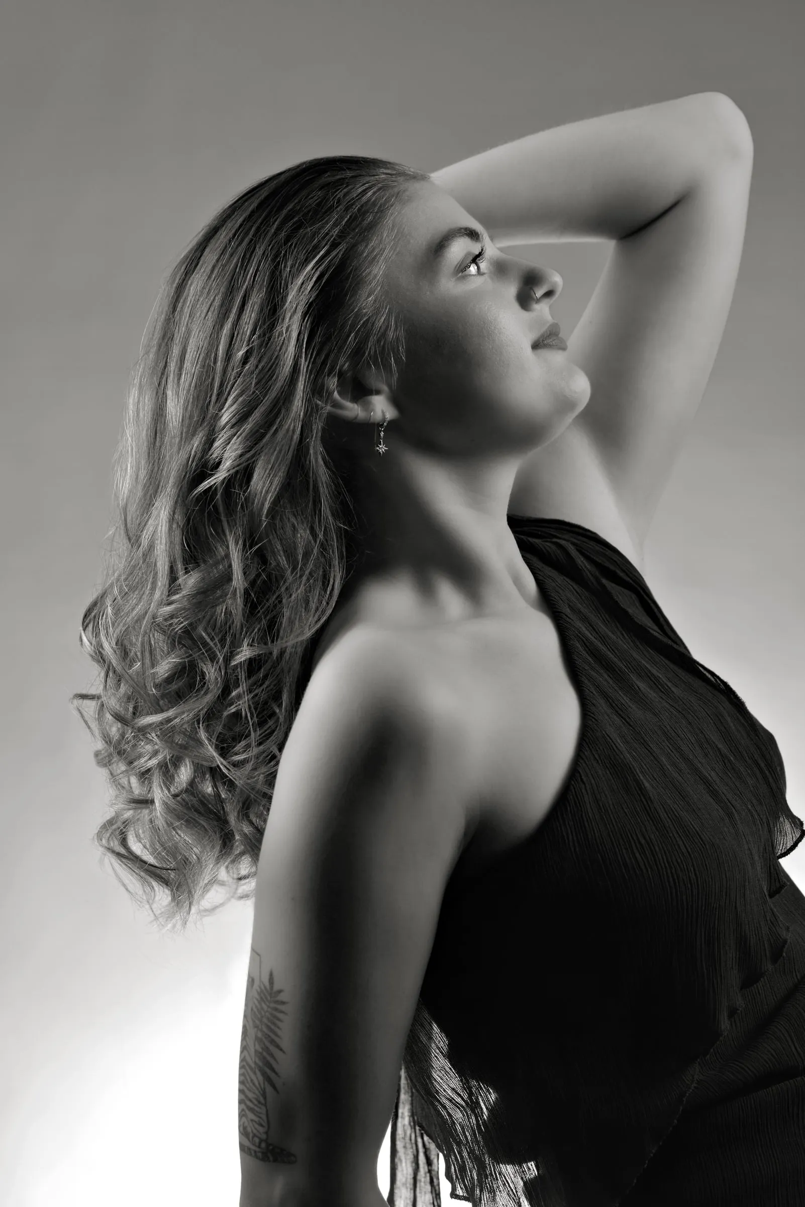 Long hair in loose, glossy waves with soft highlights, shown in profile with one arm raised