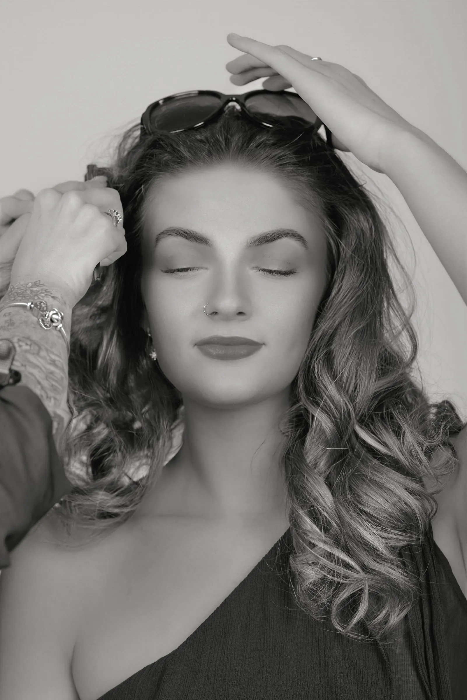 Voluminous curls being set by a stylist's hands, with sunglasses pushed up on the model's head
