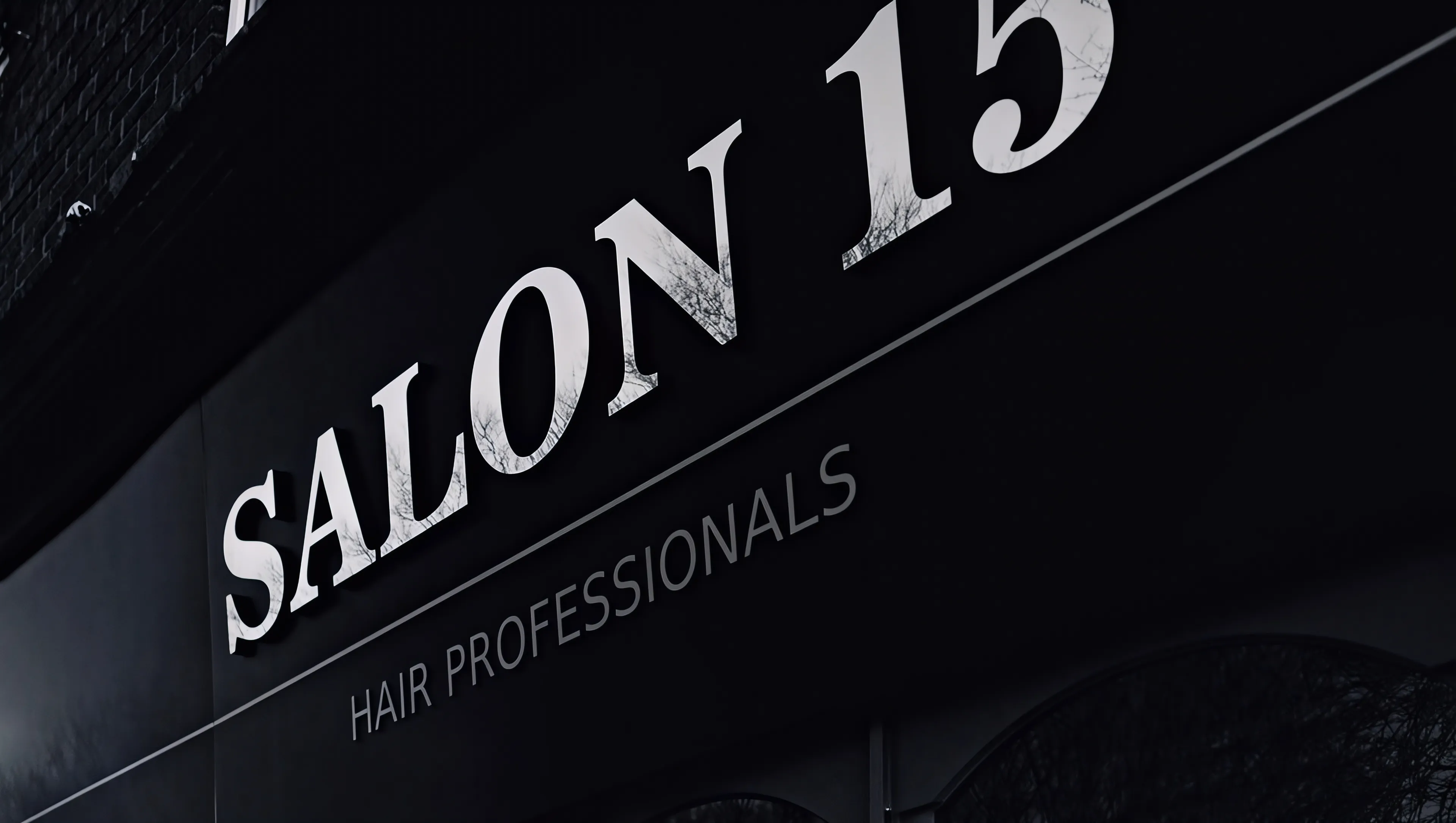 The Salon 15 shopfront in Normanton: white SALON 15 Hair Professionals lettering on a black fascia, photographed at an angle
